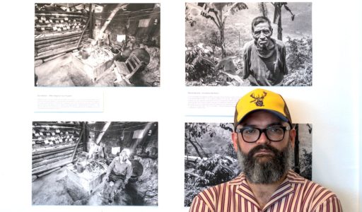 Photograph of Alejandro Flores in front of an exhibition of his photographs.